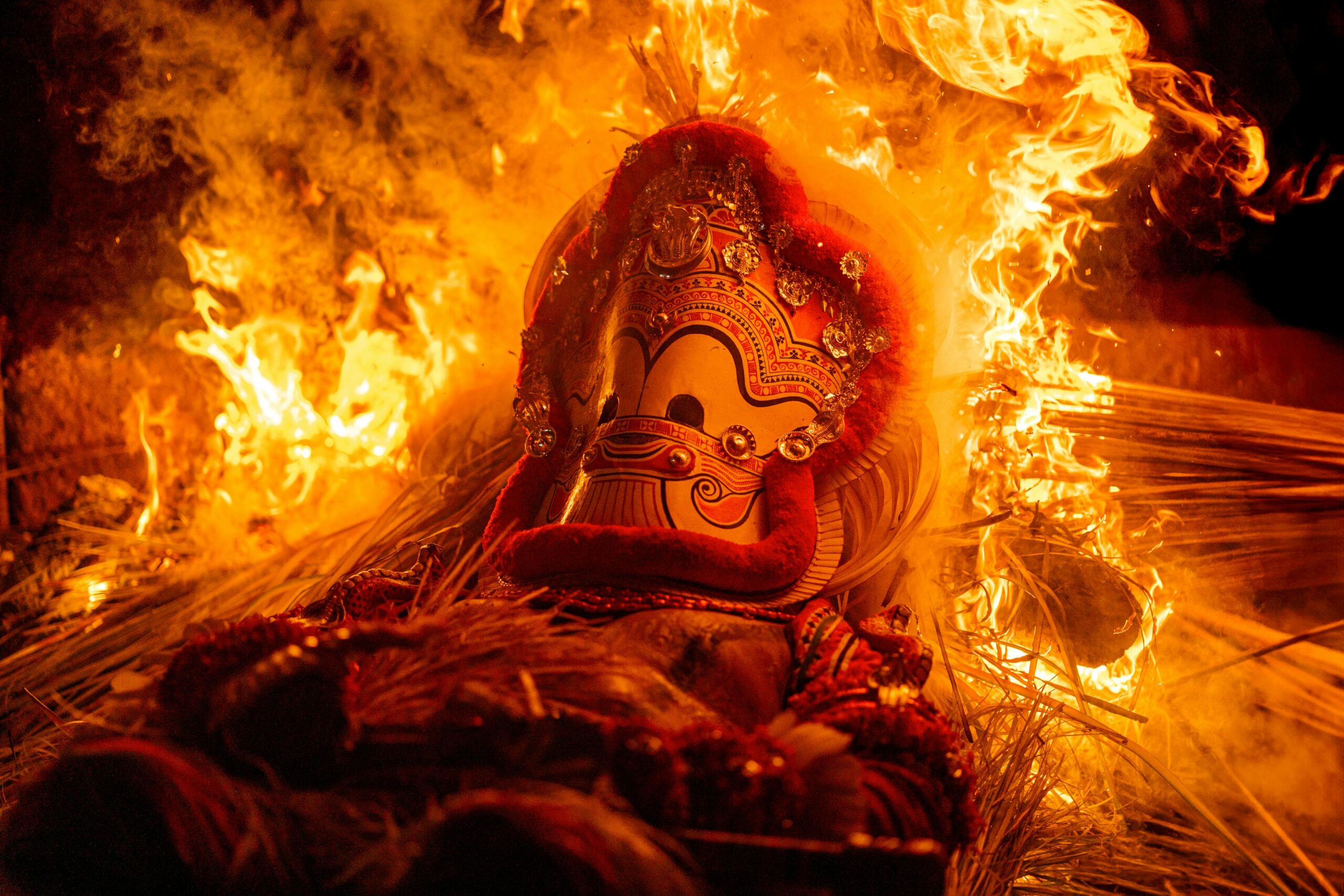Theyyam performer in towering headdress and fire-red makeup, North Kerala
