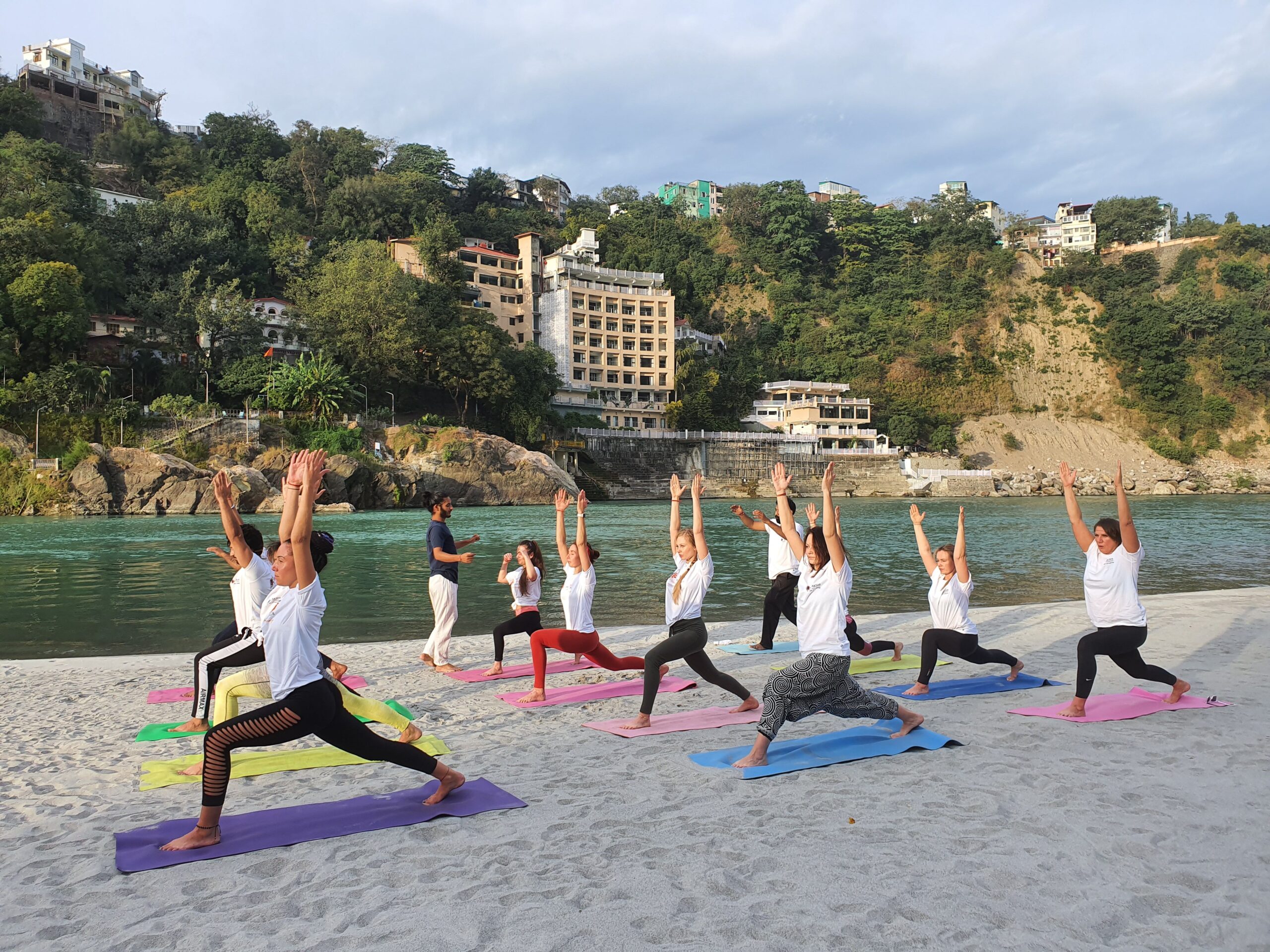 A person practising yoga by the Ganga at Rishikesh at sunrise